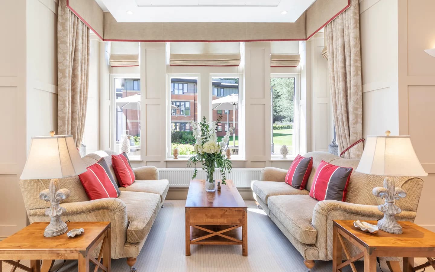 A large window with two cream sofas and red cushions