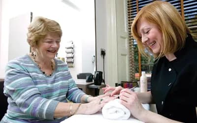 A women getting her nails done and smiling