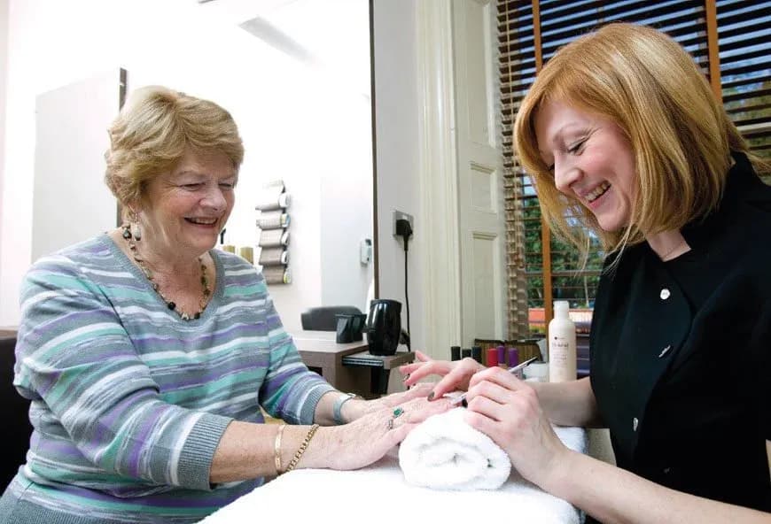 A women getting her nails done and smiling