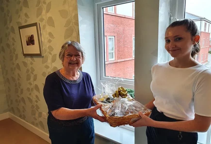 Staff presenting a gift hamper to a resident