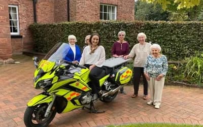 Cheshire Blood Bikes staff on a motorbike with Boughton Hall residents