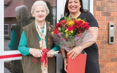 An older lady with a worker holding red flowers