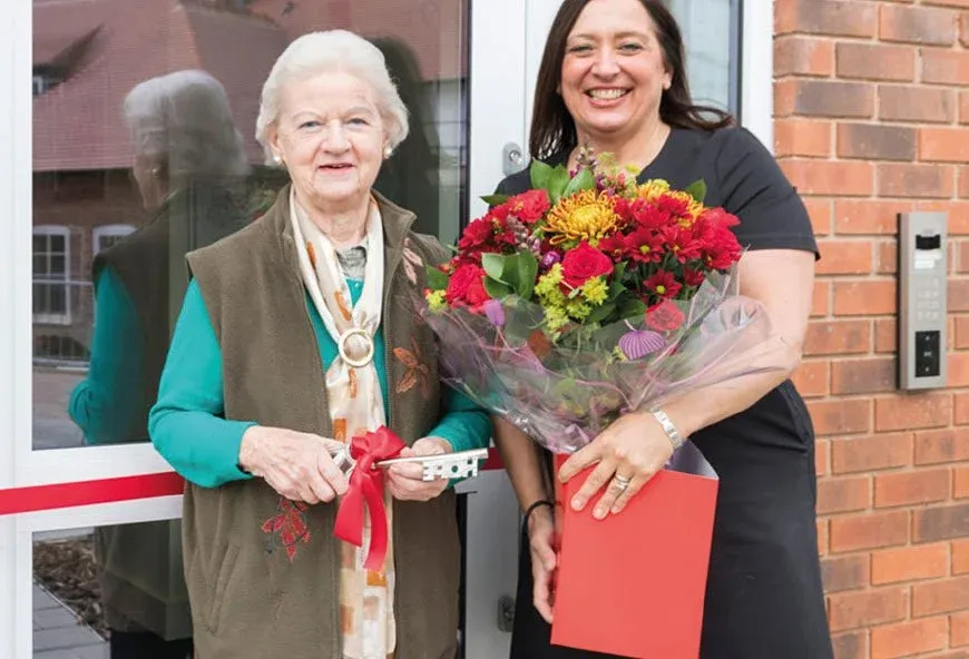 An older lady with a worker holding red flowers