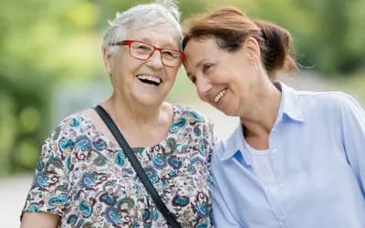 Middle aged woman stood with an older woman smiling