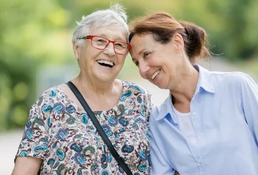Middle aged woman stood with an older woman smiling