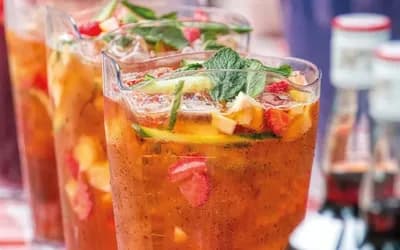 A jug of pimms with fruit and greenery in it.