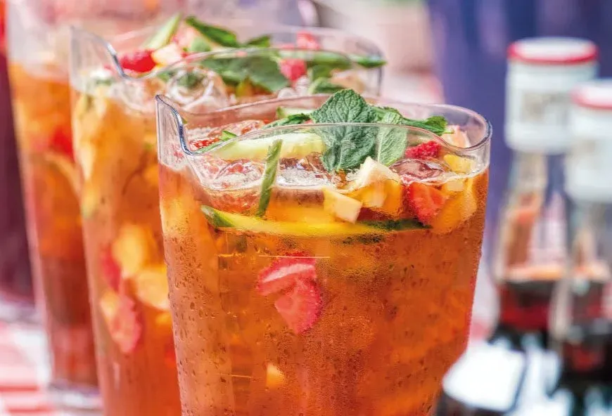 A jug of pimms with fruit and greenery in it.