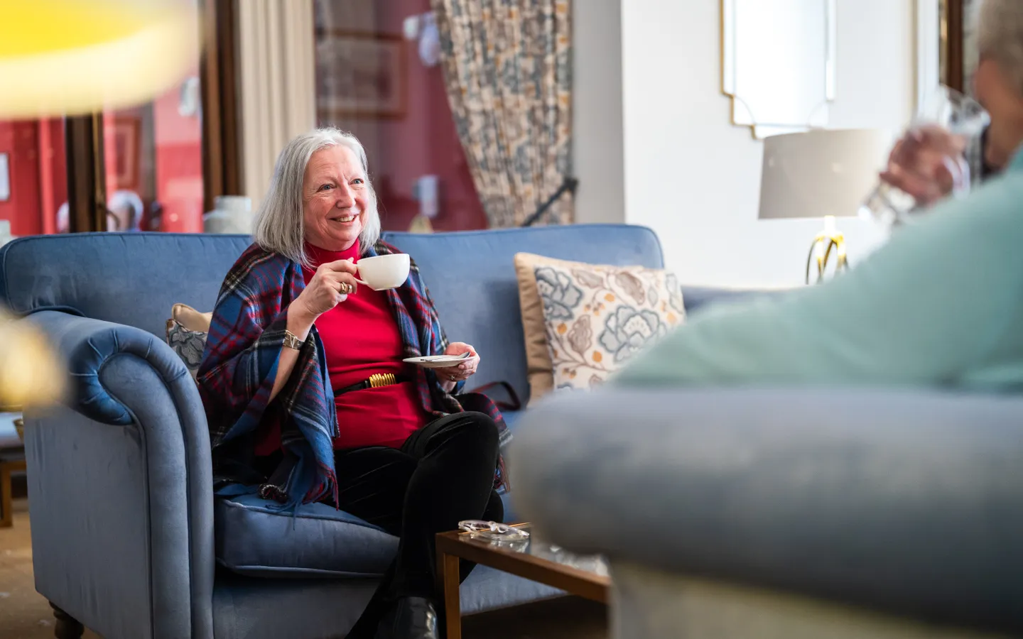Resident enjoying a cup of tea on the sofa