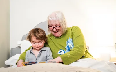 Resident reading to her grandson in bed