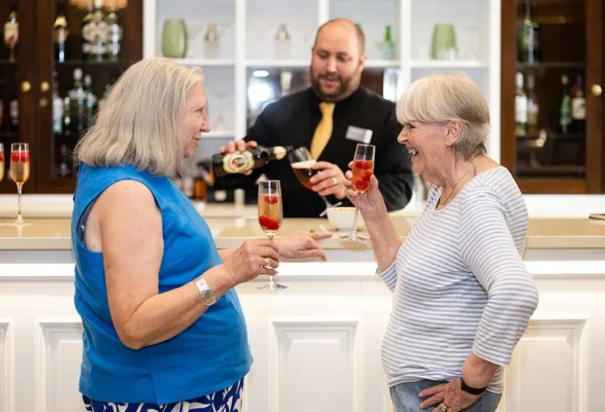 Two women with a drink cheering