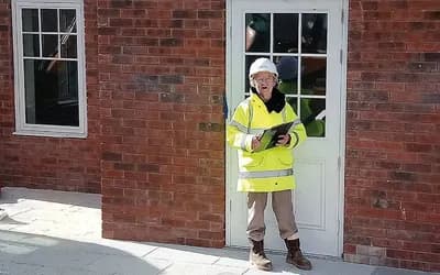 A lady in a neon jacket stood in front of the house.