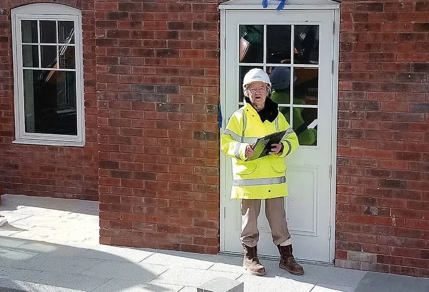 A lady in a neon jacket stood in front of the house.